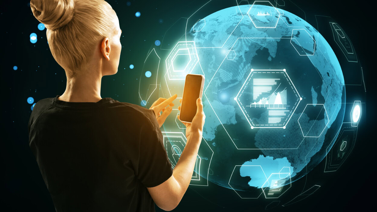 Widok z tyłu młodej blondynki używającej telefonu komórkowego z cyfrowym hologramem kuli ziemskiej na rozmytym tle Globalna technologia finansów i koncepcja bezpieczeństwa sieci