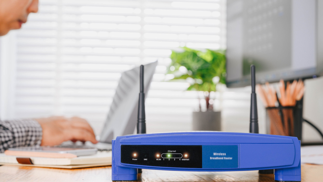 Bezprzewodowy router i mężczyzna używa laptop w biurze. router bezprzewodowy szerokopasmowy dom laptop komputer telefon wifi koncepcja