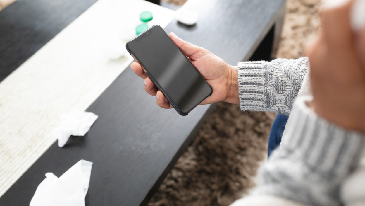 Starsza kobieta rasy mieszanej siedząca na sofie i korzystająca ze smartfona