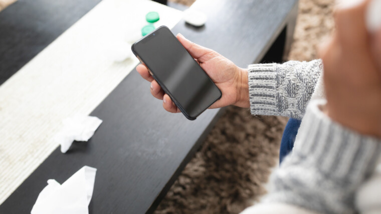 Starsza kobieta rasy mieszanej siedząca na sofie i korzystająca ze smartfona