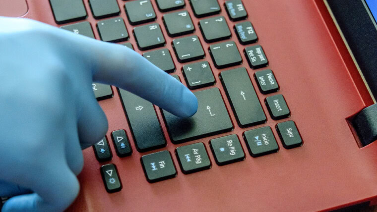 Ręka młody człowiek w medycznej rękawiczce na laptopu kluczu.