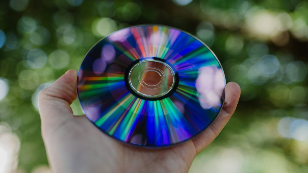 selective focus photography of person holding compact disc