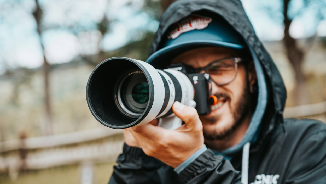 man in black jacket holding black dslr camera