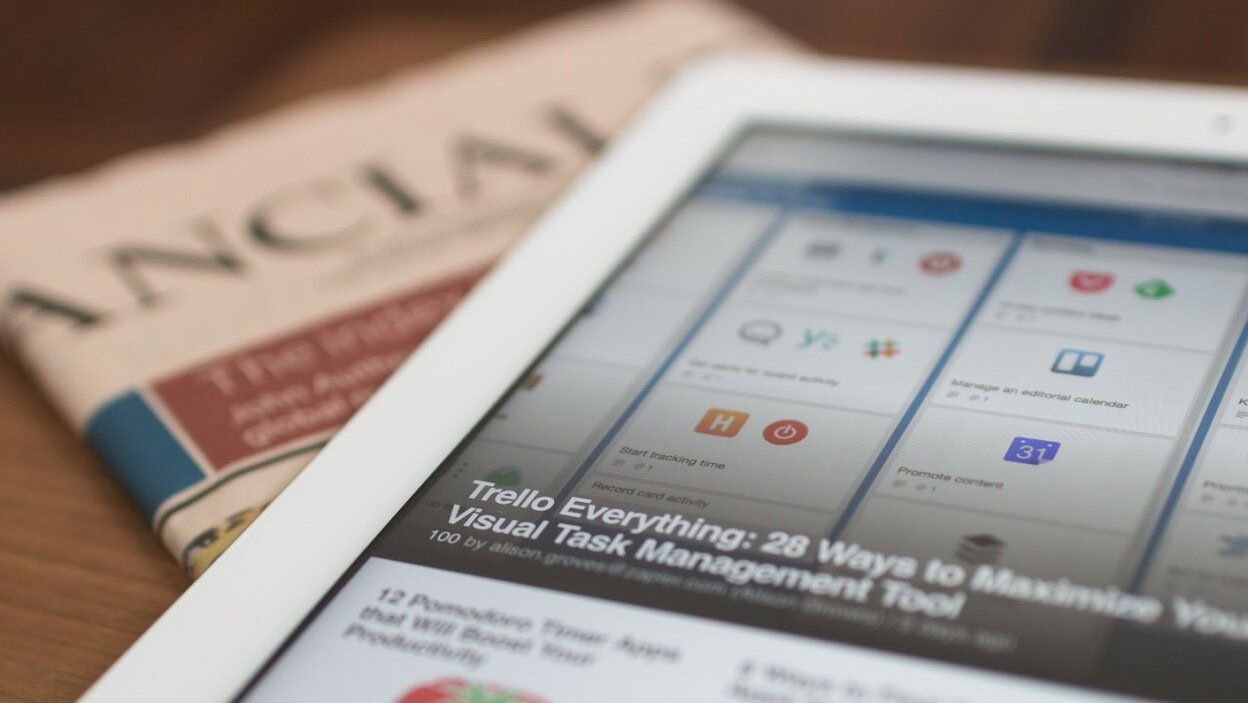 white tablet computer on top of newspaper