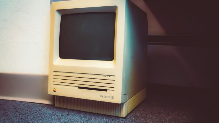 an old computer sitting on the floor next to a wall