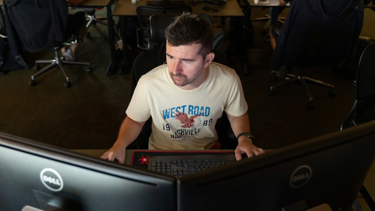 a man sitting in front of a computer monitor