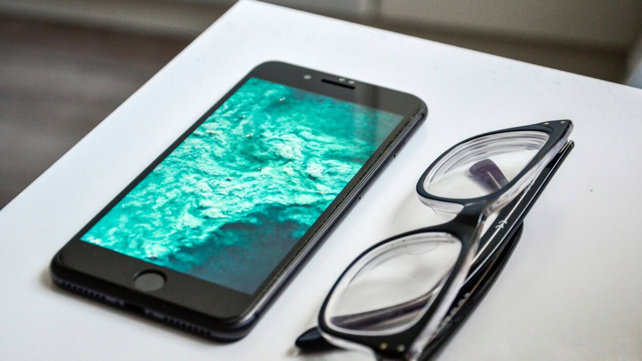 space gray iPhone 6 turn on beside eyeglasses on table