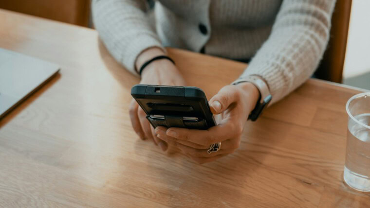 woman in white sweater holding black smartphone
